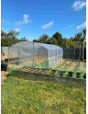 Serre Tonneau dans un potager, modèle 4 Saisons Plus, longueur 6mètres, pieds droits, largeur 4m. Ciel bleu et très beau temps.